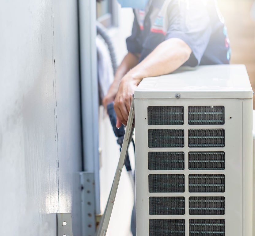 A worker looking behind an AC area and inspecting