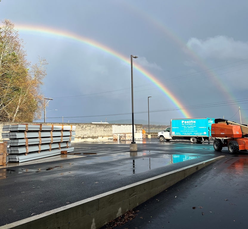 A Pacific Air Comfort truck with a double rainbow seen in the background.